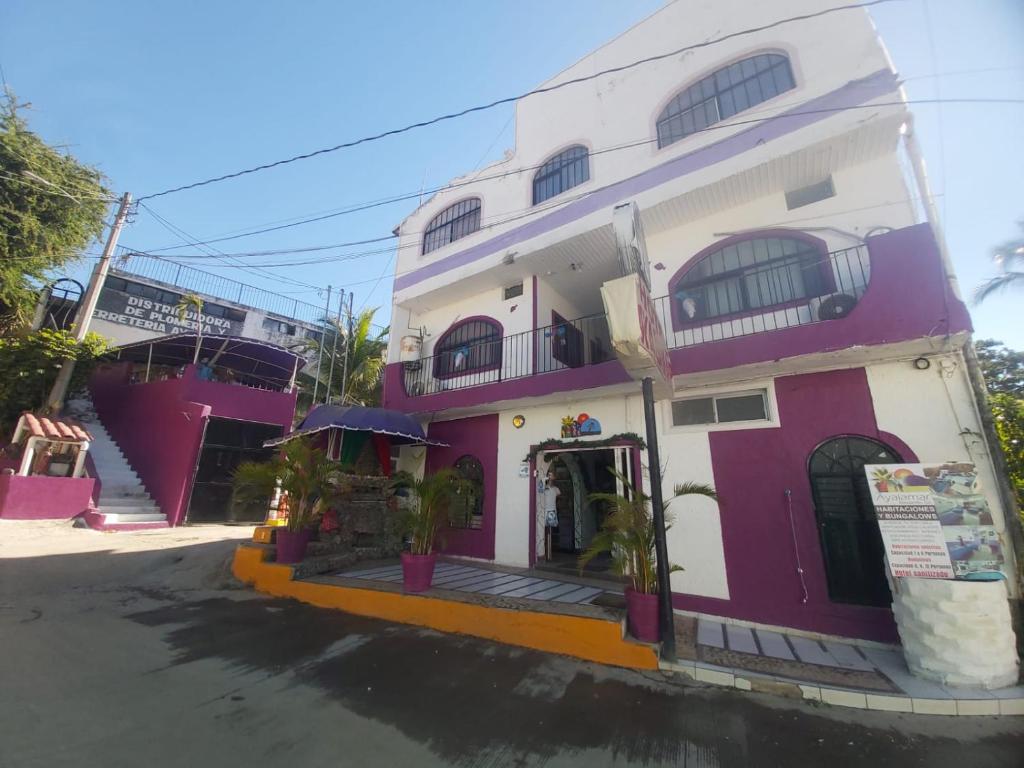 un edificio blanco y púrpura con porche en Hotel Ayalamar Manzanillo, en Manzanillo