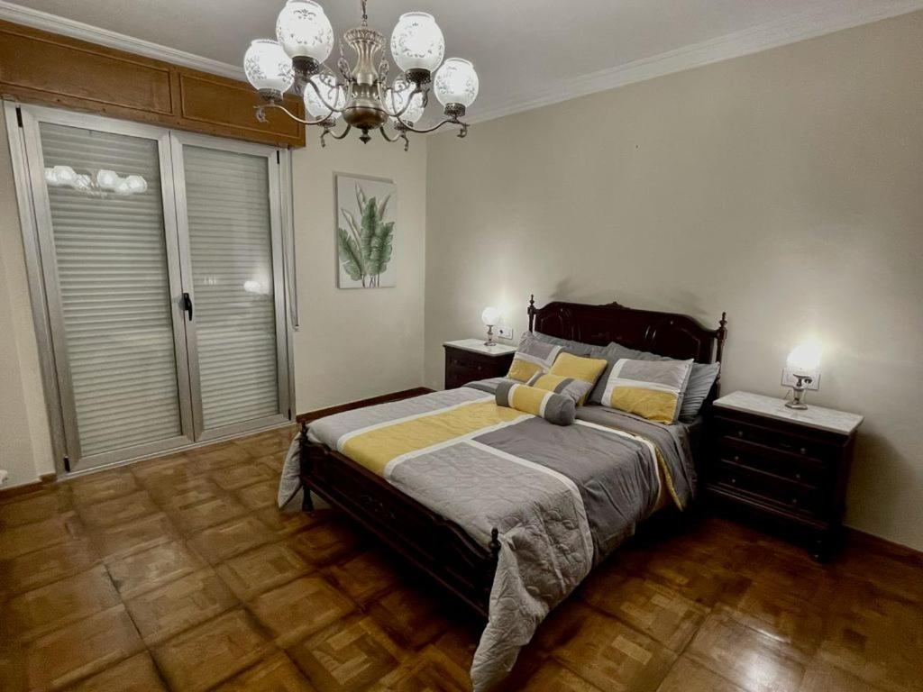Un dormitorio con una cama grande y una lámpara de araña. en PRECIOSO PISO CENTRO, en Ourense