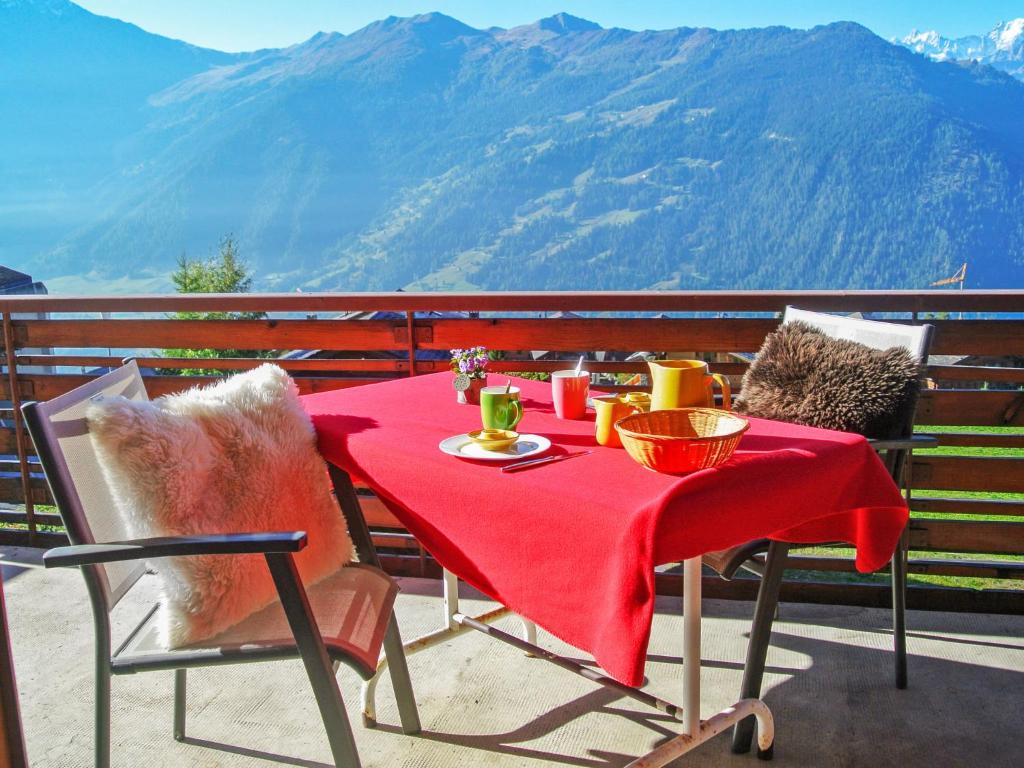 uma mesa com uma toalha de mesa vermelha numa varanda com montanhas em Apartment La Toura by Interhome em Verbier