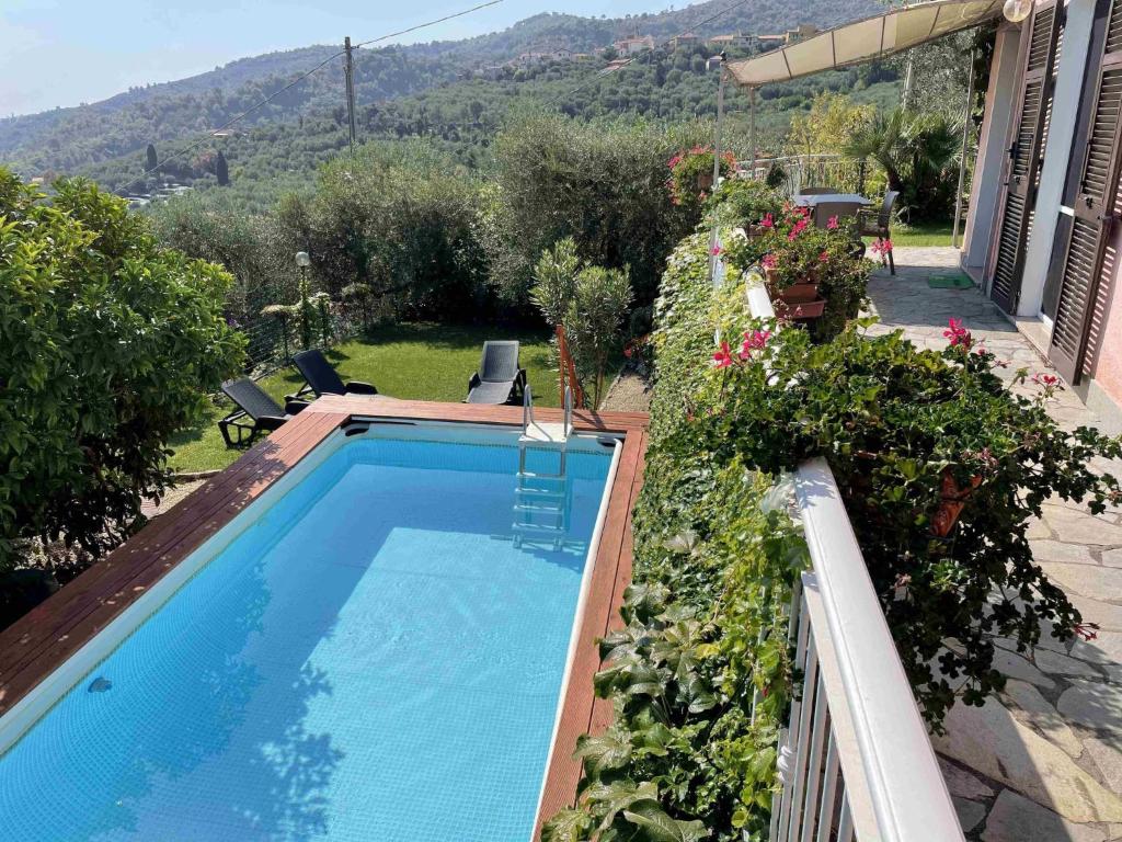 una piscina en un patio con flores y una casa en Apartment Villa Paradiso - DOL190 by Interhome, en Dolcedo