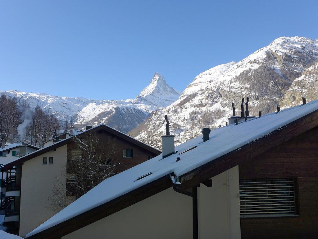pokryty śniegiem dach domu z górami w tle w obiekcie Apartment St- Martin by Interhome w mieście Zermatt