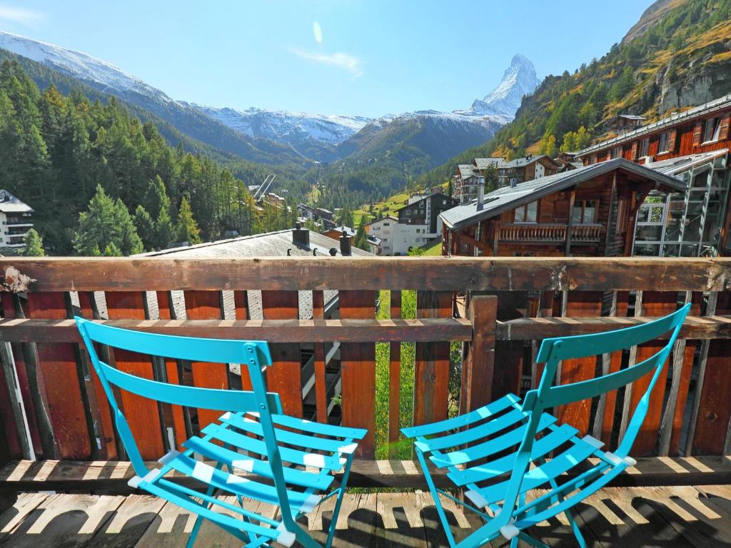ツェルマットにあるアパートメント ラウバーハウス ツェルマットの山々を望むバルコニーに座る青い椅子2脚
