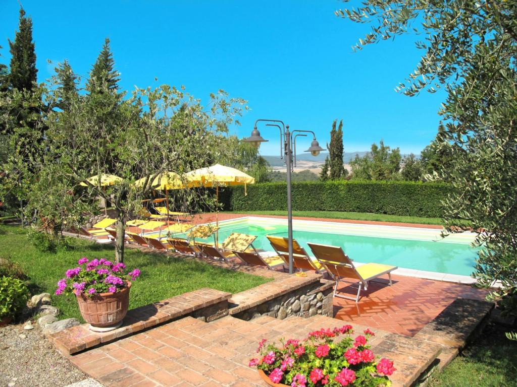 a pool with chairs and umbrellas in a yard at Apartment Casa Nuova - Volterra - LAI130 by Interhome in Fattoria Spedaletto