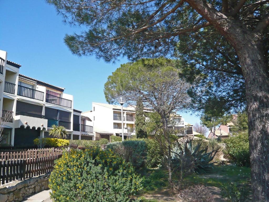 an apartment building with a tree and bushes at Apartment Les Eaux Vives 1 &amp; 2-5 by Interhome in Saint Pierre La Mer
