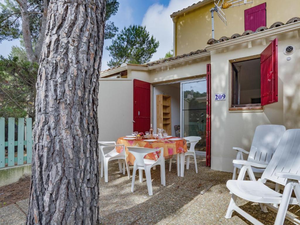 d'une terrasse avec une table, des chaises et un arbre. dans l'établissement Apartment Le Centaure by Interhome, au Cap d'Agde