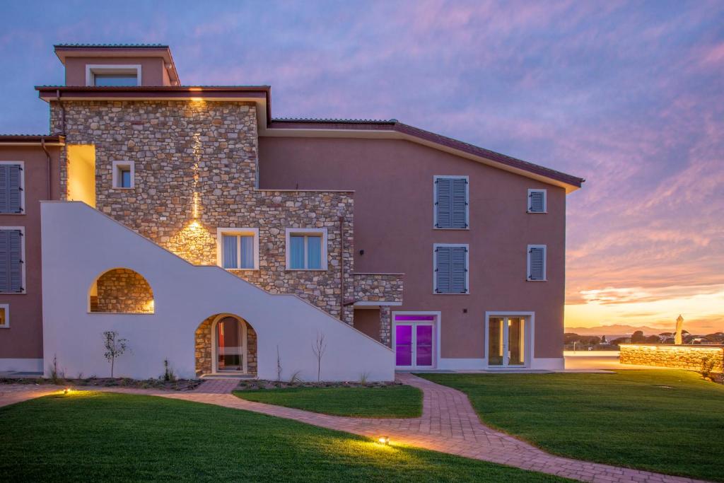a large house with a sunset in the background at Riva Toscana Golf Resort & SPA in Follonica