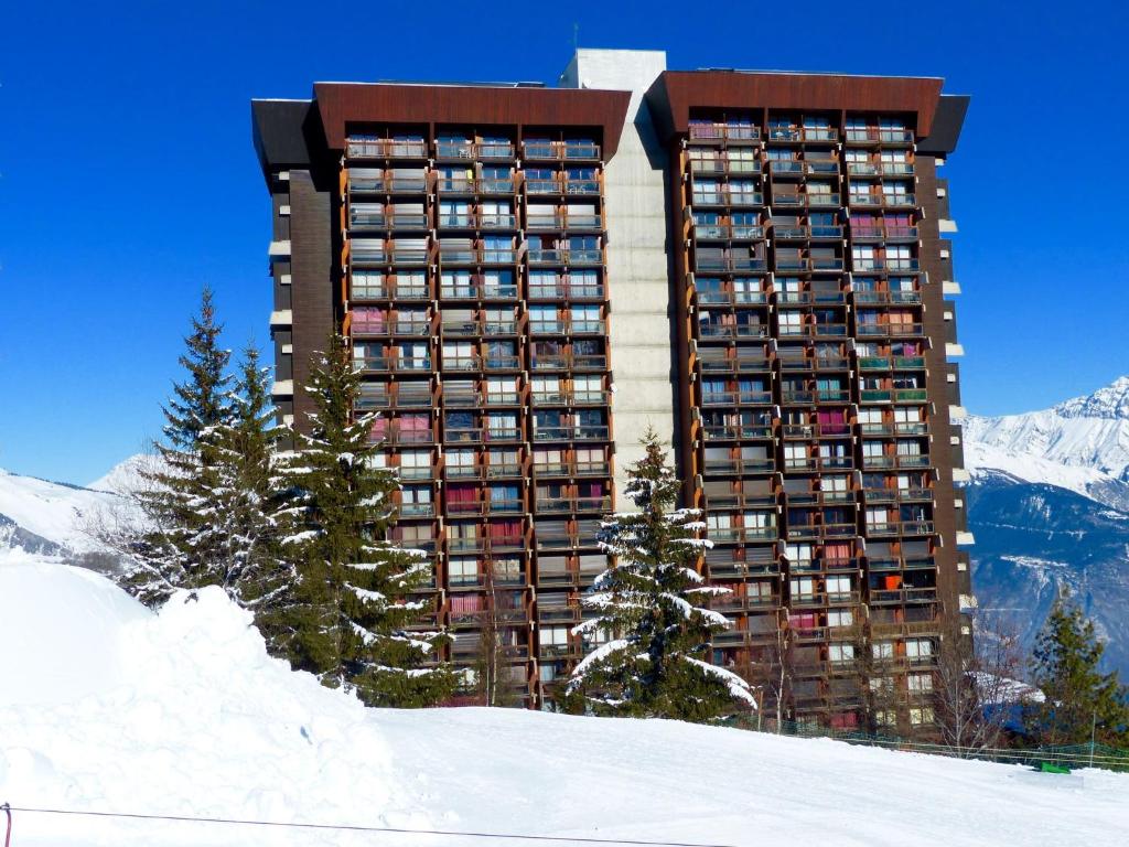 a large apartment building in the snow with mountains at Studio Pegase Phenix-44 by Interhome in Le Corbier