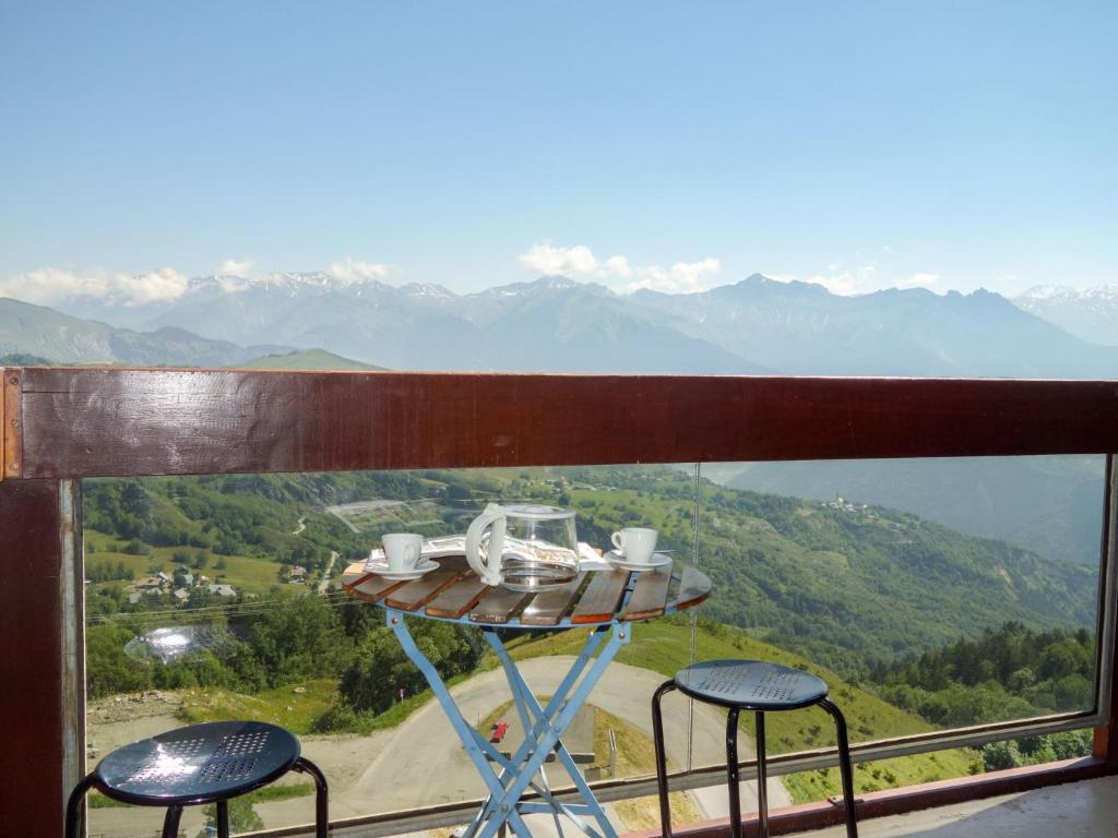 a table and two chairs on a balcony with mountains at Studio Pegase Phenix-44 by Interhome in Le Corbier