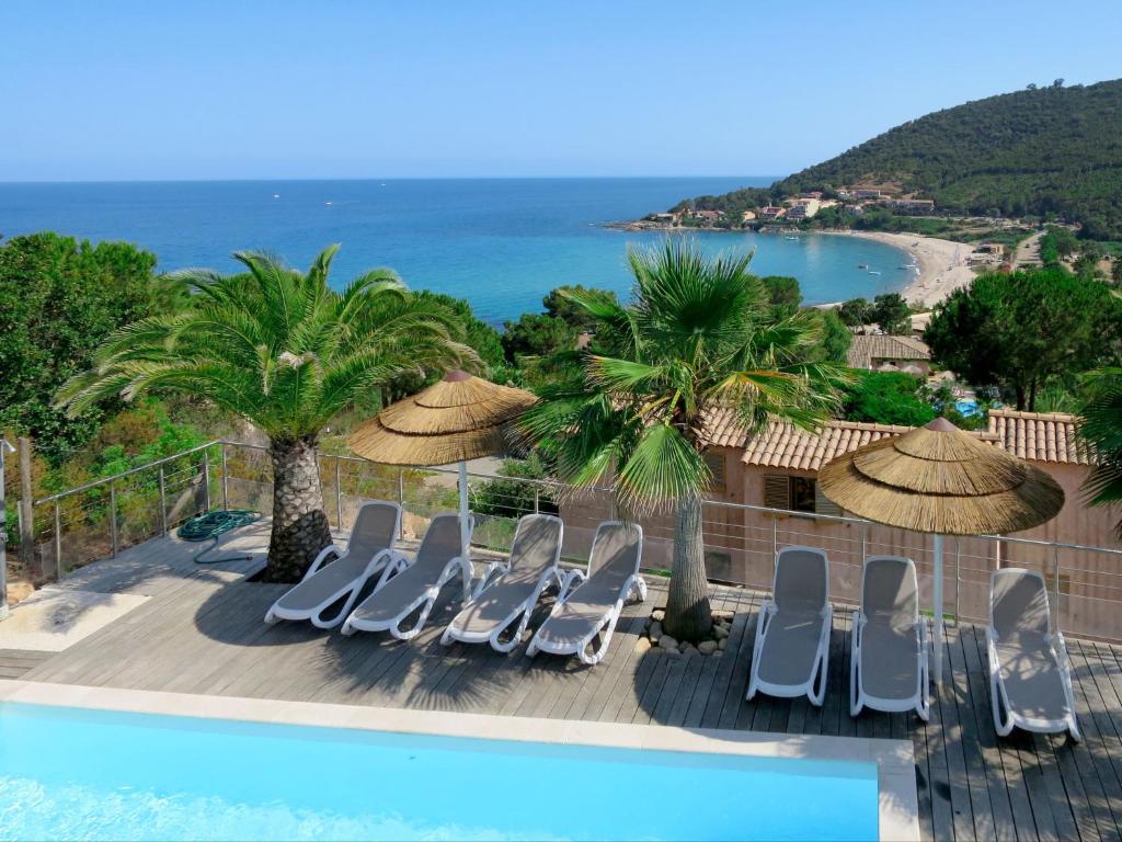 - une piscine avec chaises longues et parasols et l'océan dans l'établissement Holiday Home Villa Ottavi - TAR140 by Interhome, à Sainte-Lucie de Porto-Vecchio
