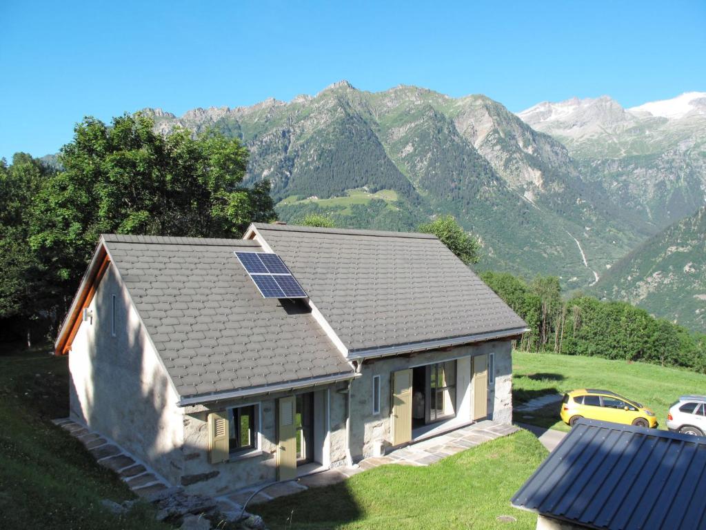 uma casa com painéis solares no telhado com montanhas em Holiday Home Rustico De Leoni by Interhome em Castro