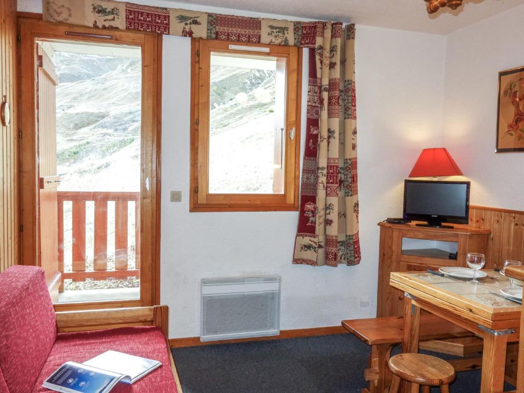 a living room with a table and a tv and two windows at Apartment La Divaria-6 in Tignes