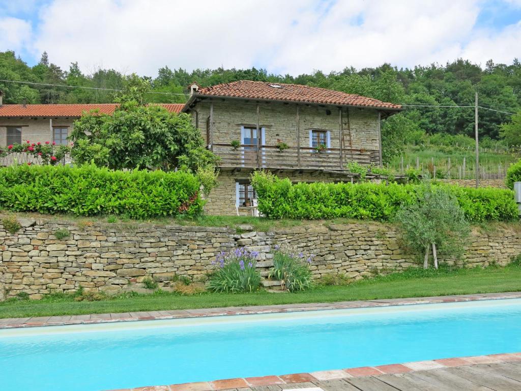 dom za kamienną ścianą obok basenu w obiekcie Holiday Home Casetta by Interhome w mieście Cortemilia
