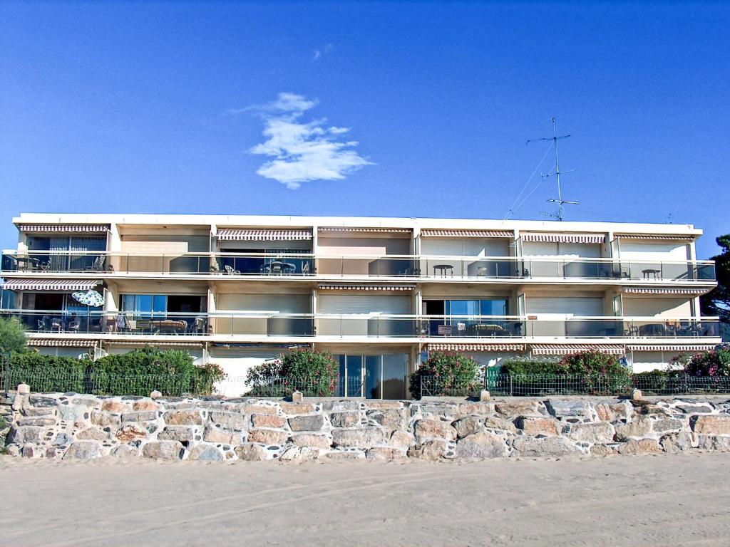 a large building on the beach next to a stone wall at Apartment De la Plage-1 by Interhome in Cavalaire-sur-Mer