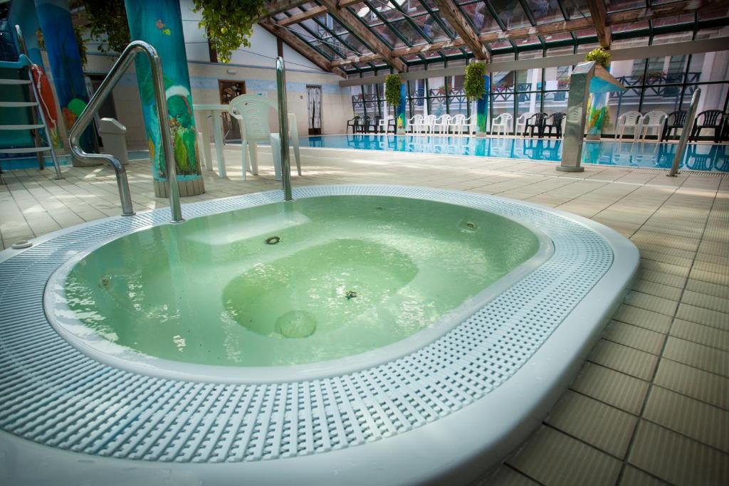 Circular indoor hot tub with bubbling water beside a larger hotel pool in spa area