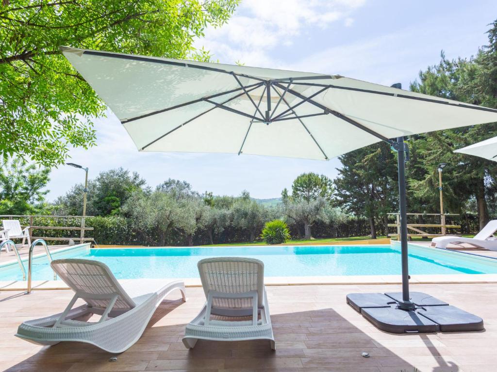 einen Pool mit 2 Stühlen und einem Sonnenschirm in der Unterkunft Holiday Home Casale Vidorni by Interhome in Chiavelli