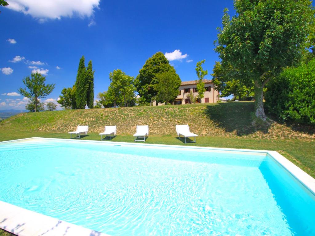 a swimming pool with chairs and a house at Holiday Home Montebello by Interhome in Monterchi