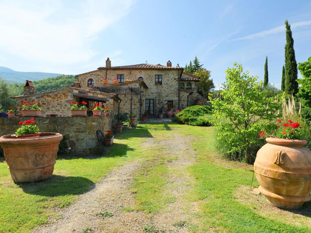 una vieja casa de piedra con dos grandes macetas de flores en Holiday Home Poggio Velluto by Interhome, en Seggiano