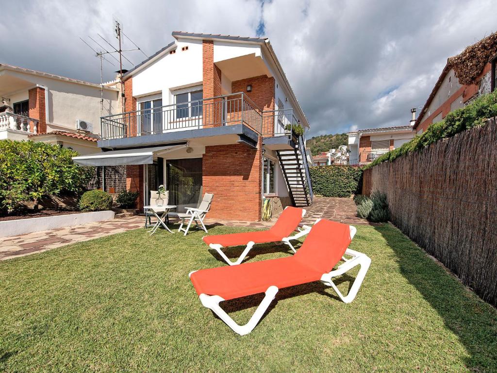 two red chairs sitting on the grass in front of a house at Holiday Home Estiu by Interhome in Pineda de Mar