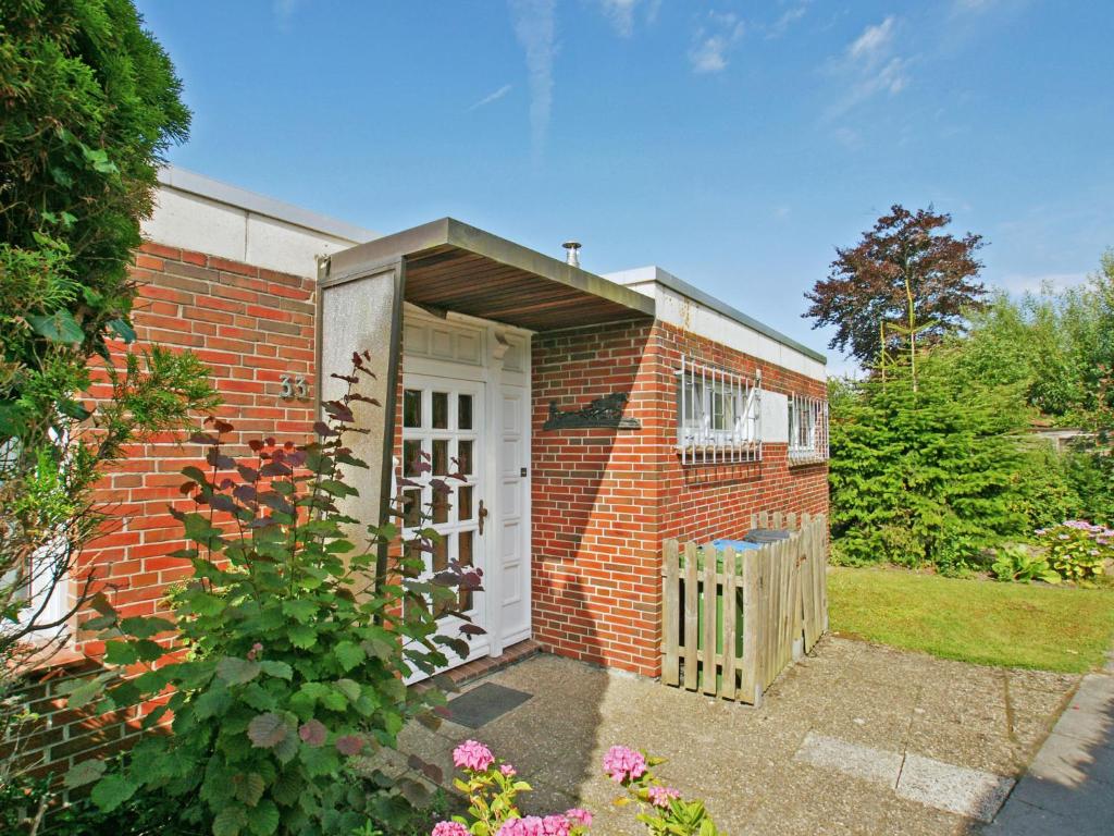 ein Backsteingebäude mit einer weißen Tür und einem Tor in der Unterkunft Holiday Home Albatross by Interhome in Norddeich