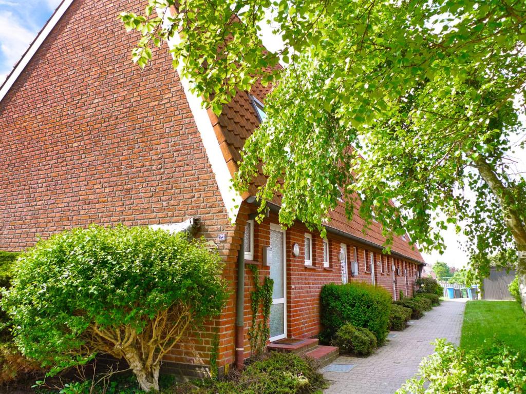 ein rotes Backsteingebäude mit einem Baum davor in der Unterkunft Holiday Home Koralle-1 by Interhome in Norddeich