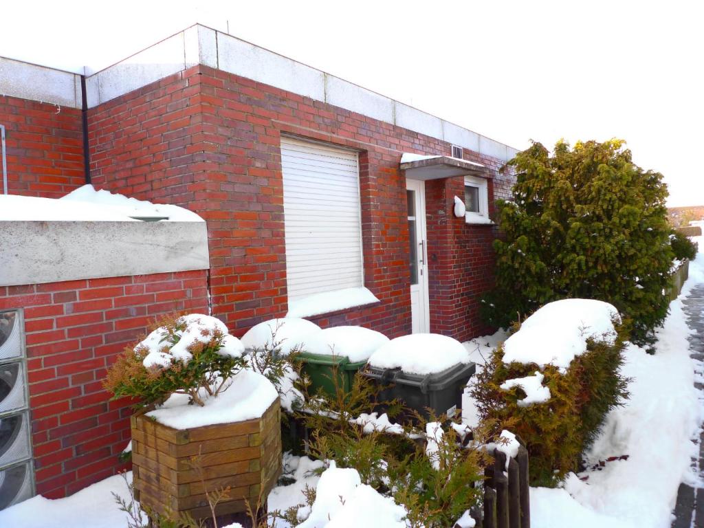 ein rotes Backsteinhaus mit Schnee darauf in der Unterkunft Holiday Home Sonnenschein by Interhome in Norddeich