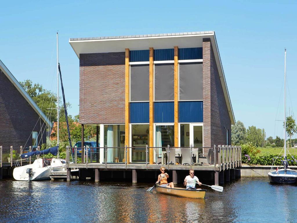 twee personen in een boot voor een gebouw bij Villa Krekt Oer 't Wetter by Interhome in Uitwellingerga