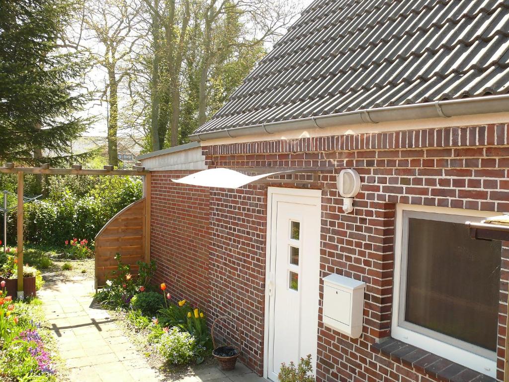 a brick house with a white door and a garden at Holiday Home Schäfer by Interhome in Norden