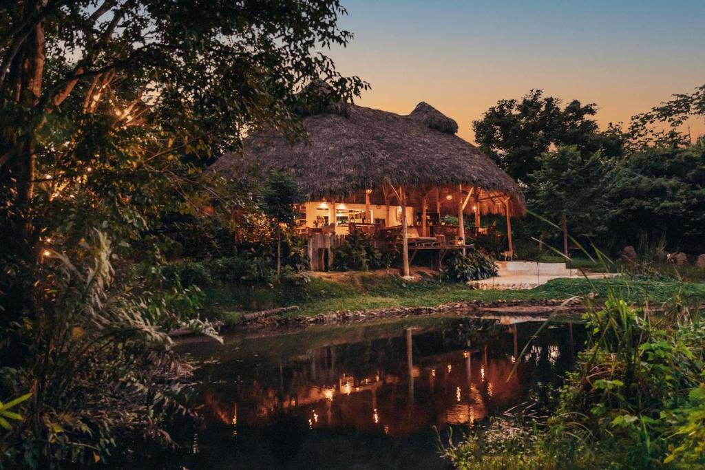 una cabaña con techo de paja junto a un cuerpo de agua en El Valle Lodge, en El Valle