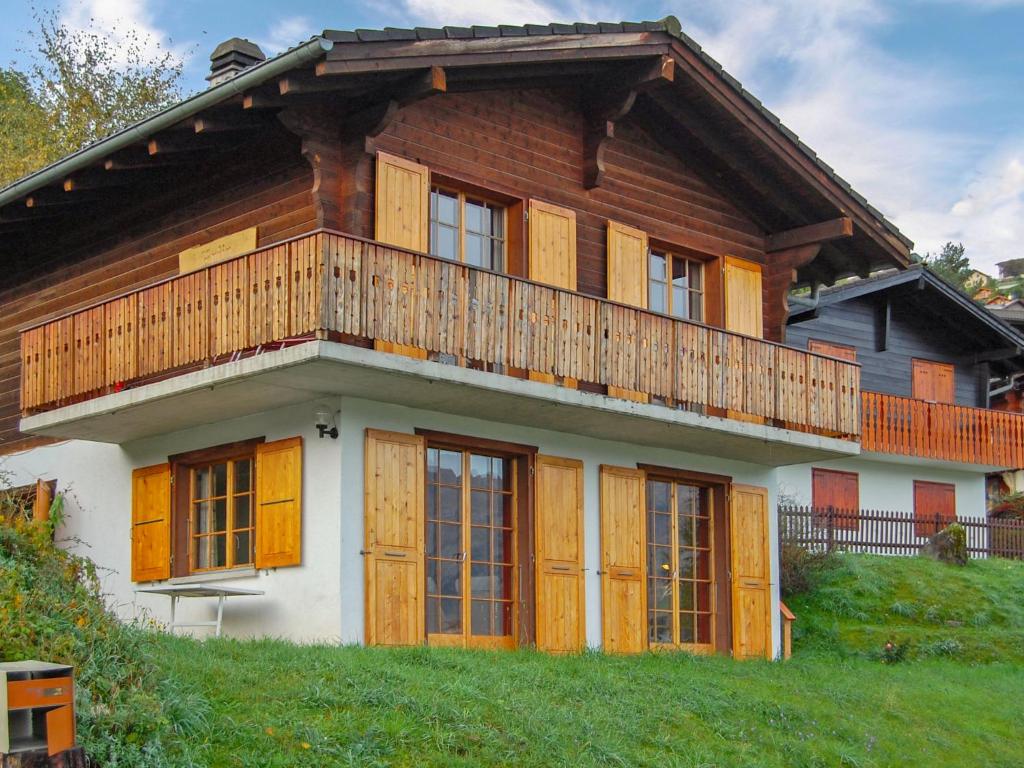 een huis met houten deuren en een balkon erboven bij Chalet Chalet Enfin by Interhome in Nendaz