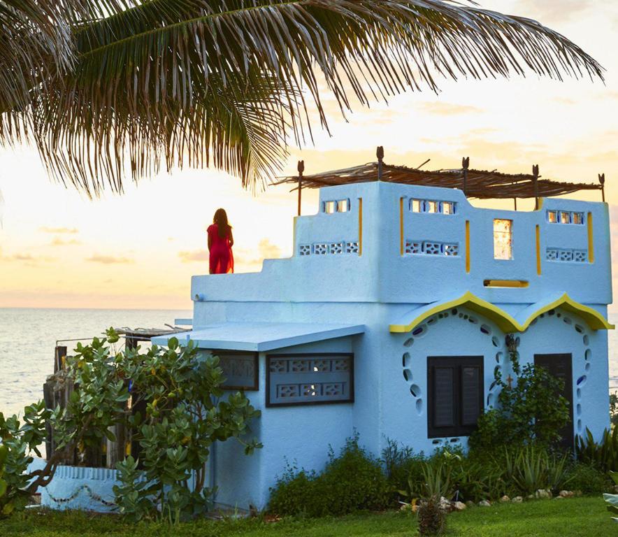 a woman standing on top of a blue house at Jakes Hotel in Treasure Beach