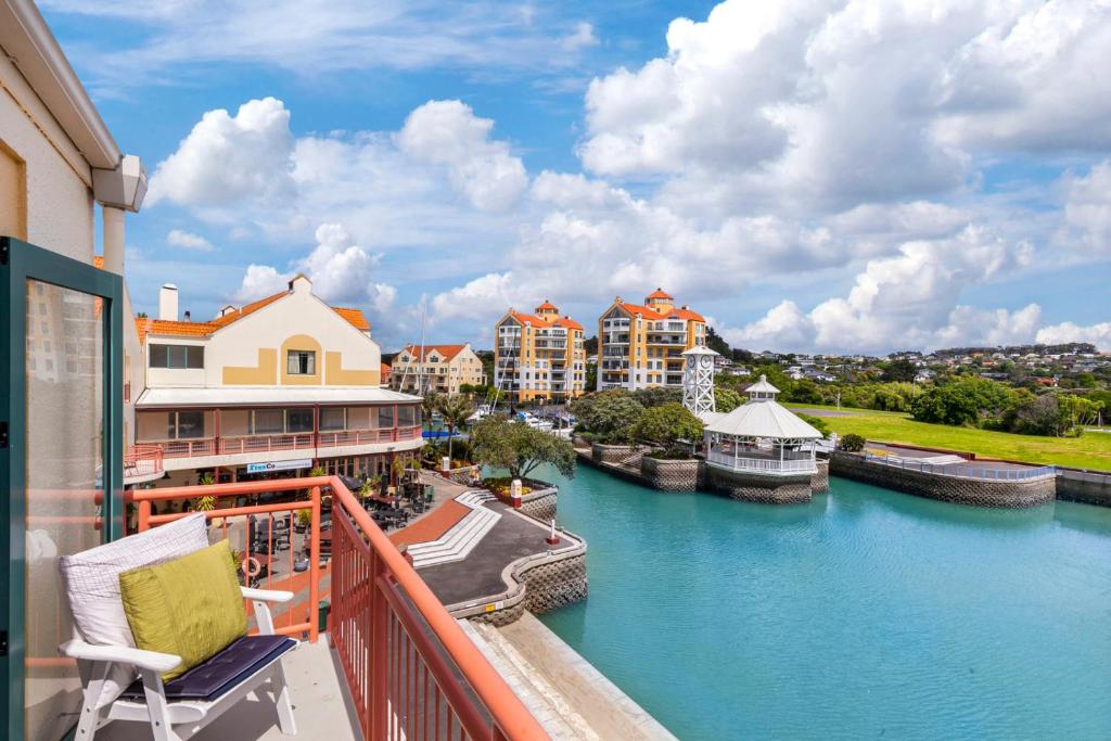 balcón con vistas al río y a los edificios en Harbourside Haven - Whangaparāoa Studio Apartment, en Te Whanga