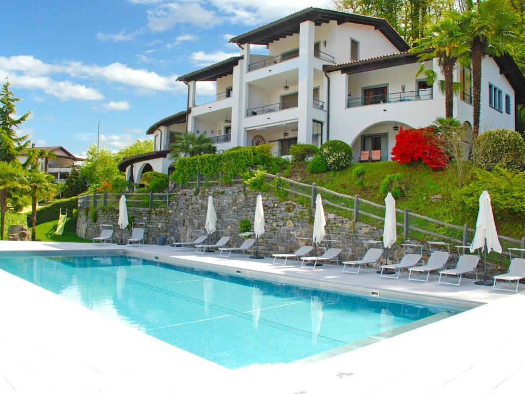 une villa avec une piscine en face d'un bâtiment dans l'établissement Apartment Miralago - Utoring-21 by Interhome, à Piazzogna