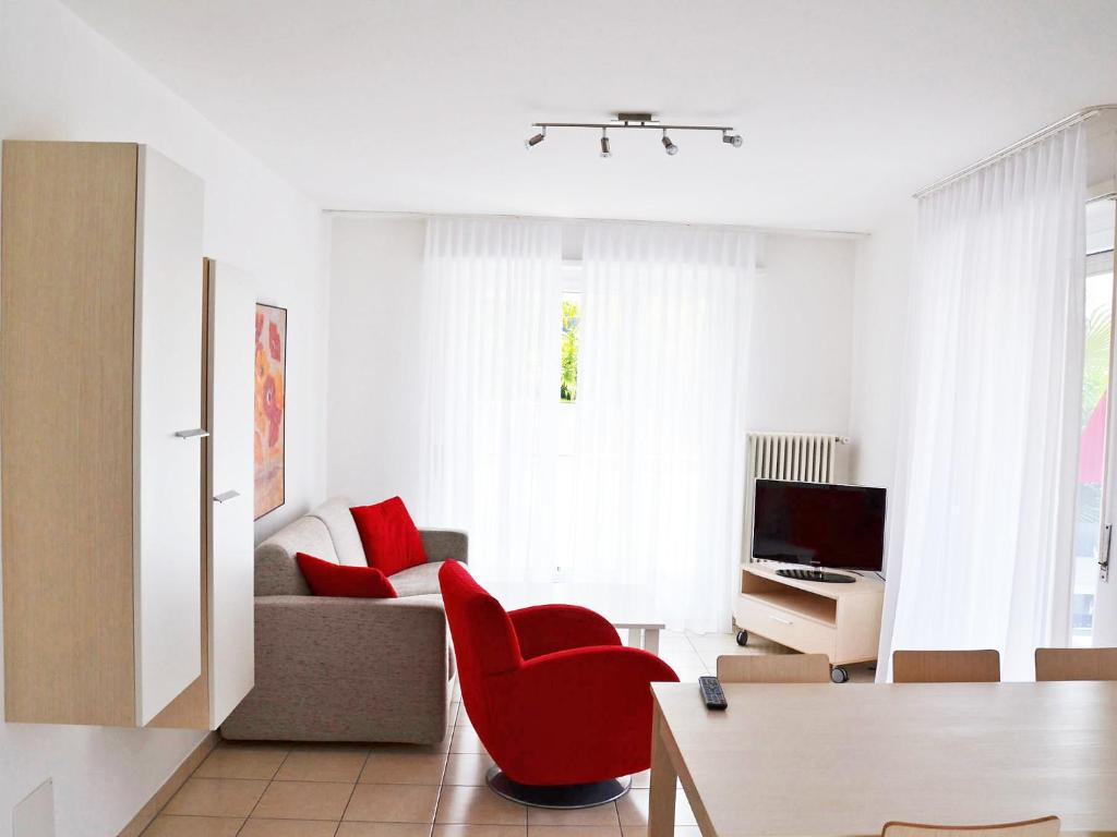 ein Wohnzimmer mit einem roten Stuhl und einem Sofa in der Unterkunft Apartment Corallo - Utoring-22 by Interhome in Ascona