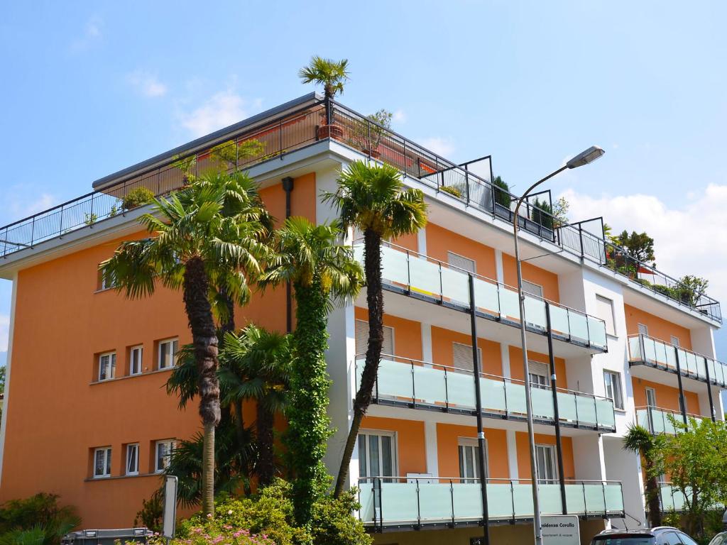 an orange building with palm trees in front of it at Apartment Residenza Corallo-7 by Interhome in Ascona