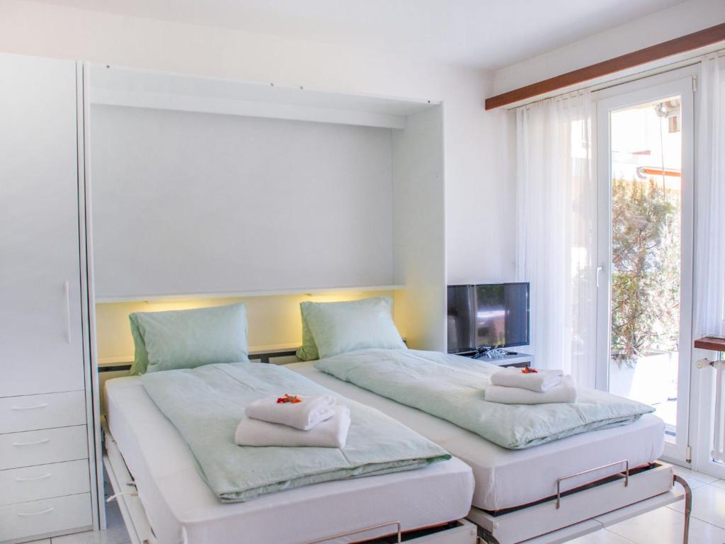 two beds in a room with a window at Apartment Residenza Lido-1 by Interhome in Locarno