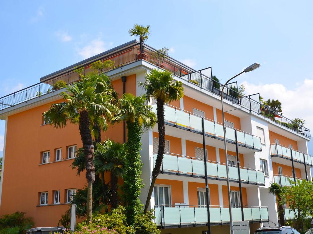 un bâtiment oranger avec des palmiers devant lui dans l'établissement Apartment Corallo - Utoring-1 by Interhome, à Ascona