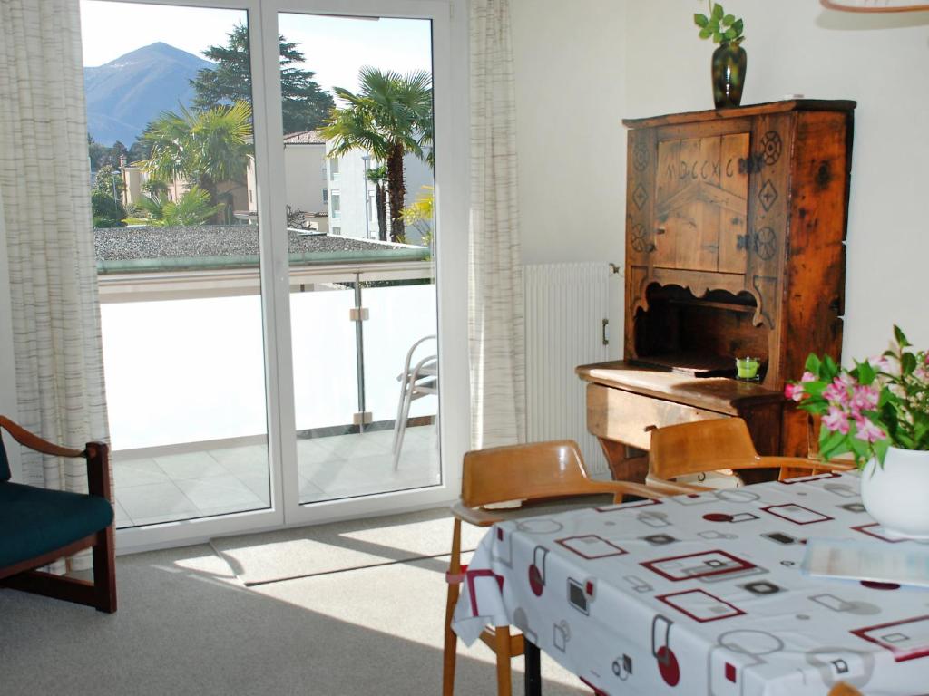 ein Wohnzimmer mit einem Tisch und einem großen Fenster in der Unterkunft Apartment Corallo - Utoring-20 by Interhome in Ascona
