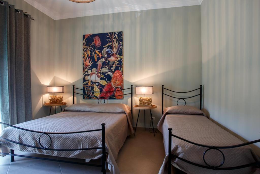 Alloggi Villa Sarsina في أنزيو: سريرين في غرفة مع لوحة على الحائط