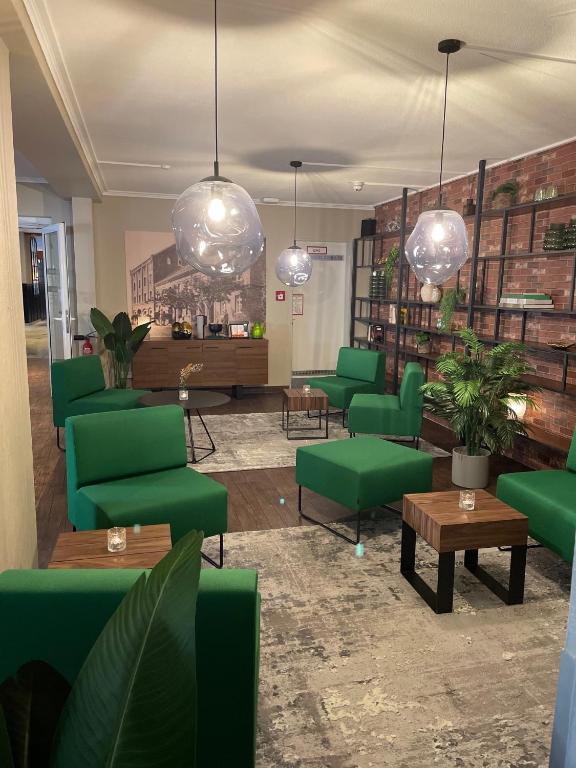 ein Wartezimmer mit grünen Stühlen, Tischen und Lichtern in der Unterkunft Hotel Dampfmühle in Neukirchen-Vluyn