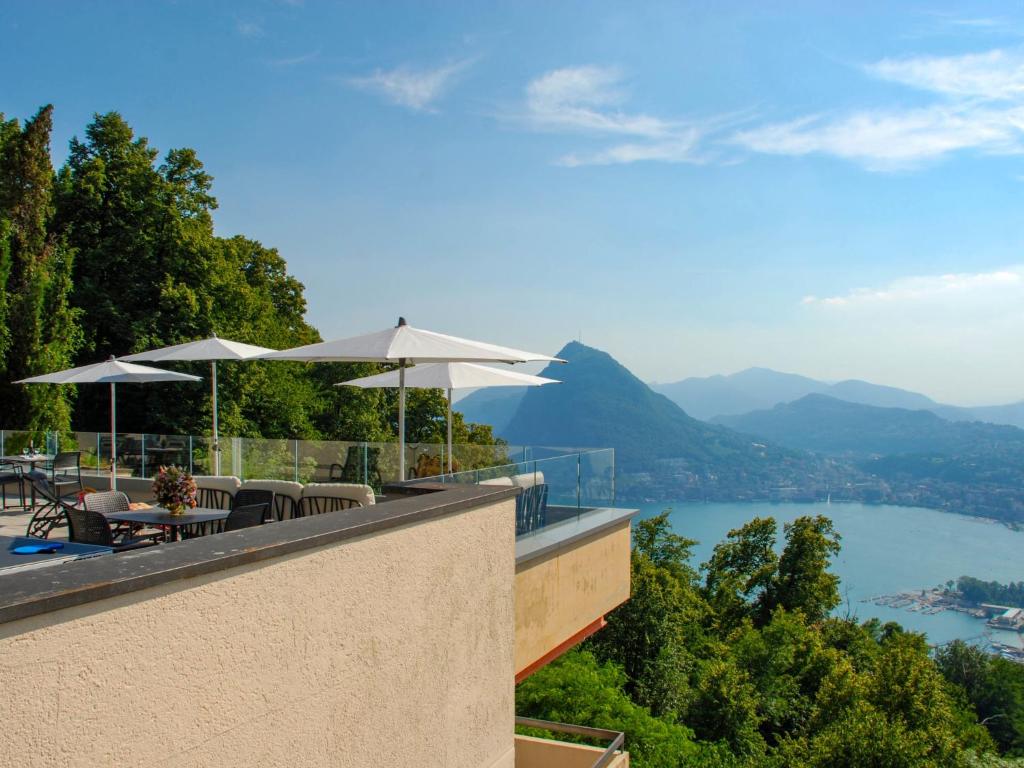 einen Balkon mit Tischen und Sonnenschirmen und Seeblick in der Unterkunft Apartment Aldesago Monte Brè - Utoring-28 by Interhome in Viganello