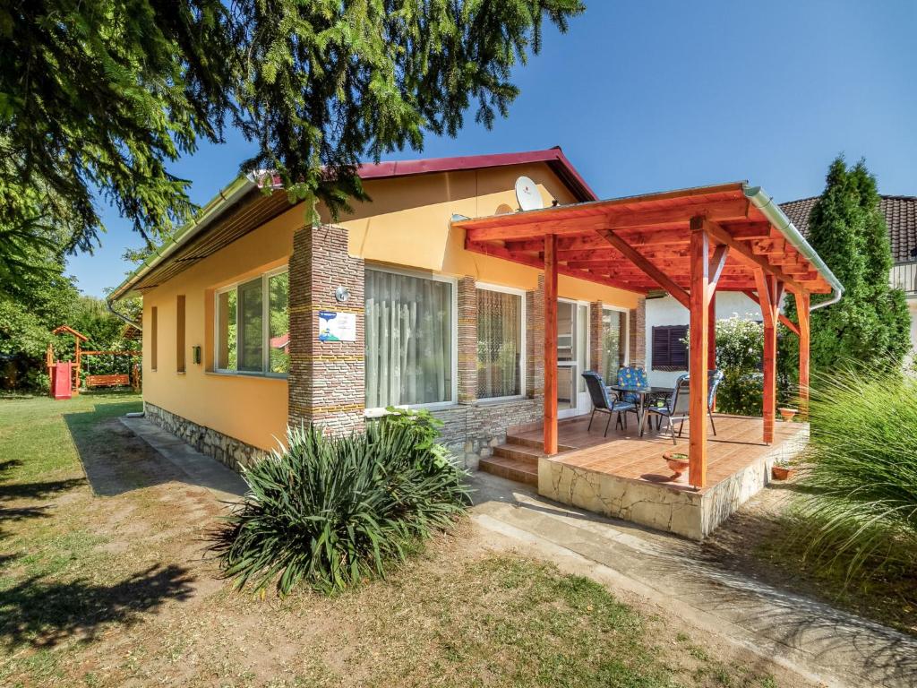 mały żółty dom z drewnianą pergolą w obiekcie Holiday Home Sunny by Interhome w mieście Balatonkeresztúr