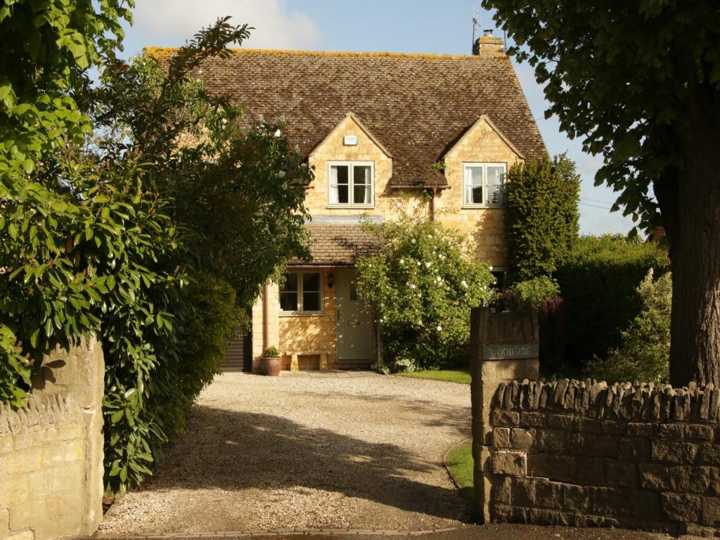 an old stone house with a gate into a driveway at Woodside Cottage in Chipping Campden