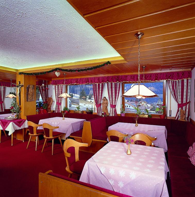 restauracja z białymi stołami i krzesłami oraz oknem w obiekcie Hotel Val w mieście Selva di Val Gardena