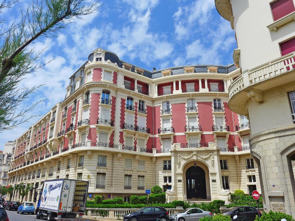 a large pink building with cars parked in front of it at Apartment Carlton-1 by Interhome in Biarritz