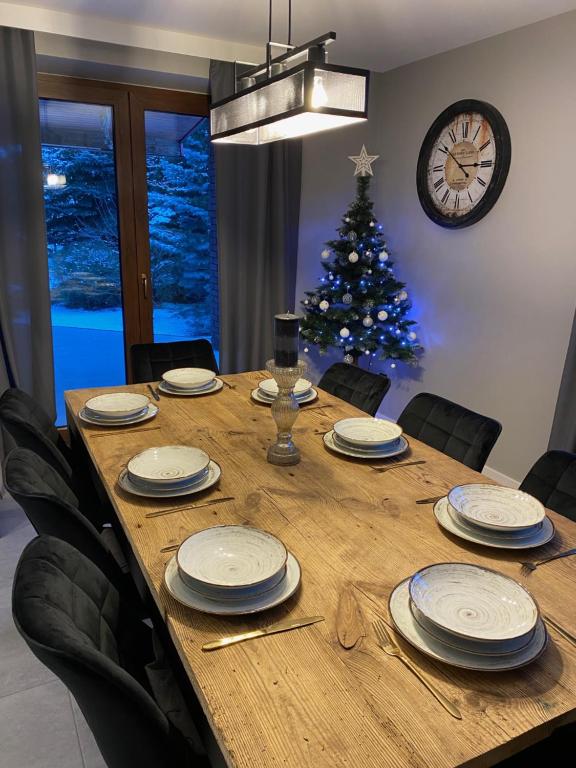 a dining room table with chairs and a christmas tree at Dom Malowy Sad in Zalesie