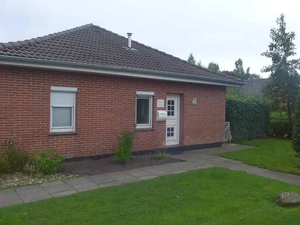 ein rotes Backsteinhaus mit einem Rasenplatz in der Unterkunft Holiday Home Norderney by Interhome in Norddeich