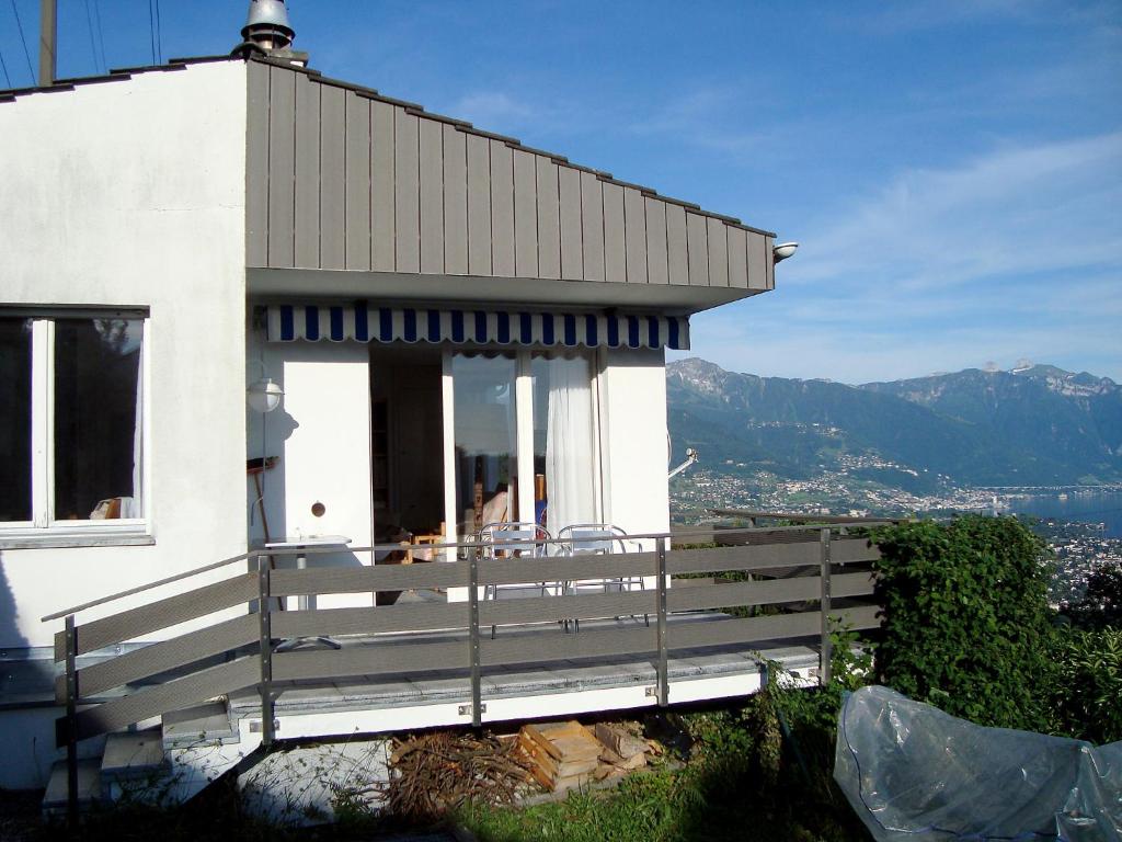 uma casa branca com uma varanda com montanhas ao fundo em Holiday Home Noisette by Interhome em Chardonne