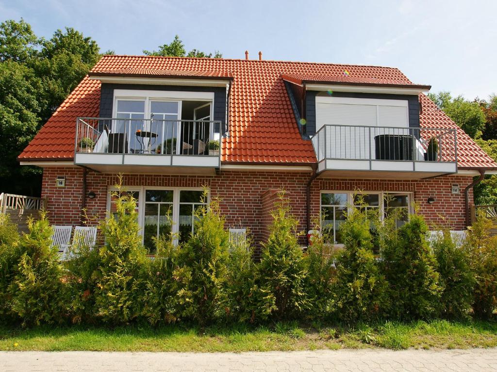 Casa de ladrillo rojo con balcón y matorrales en Apartment Osterriede by Interhome, en Norddeich