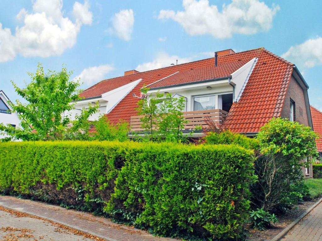 ノルトダイヒにあるApartment Seemöwe by Interhomeの赤い屋根と緑の生垣のある家