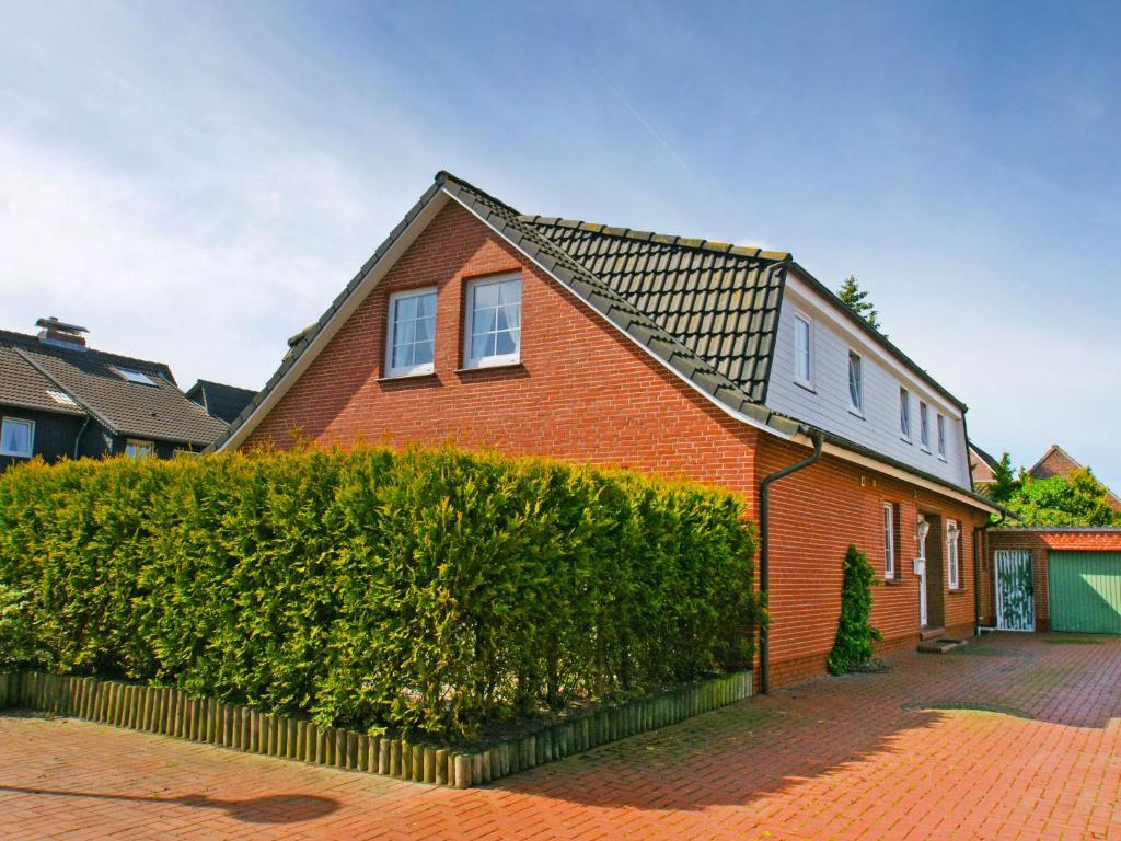 a red brick house with a hedge in front of it at Apartment Strandkorb by Interhome in Norddeich